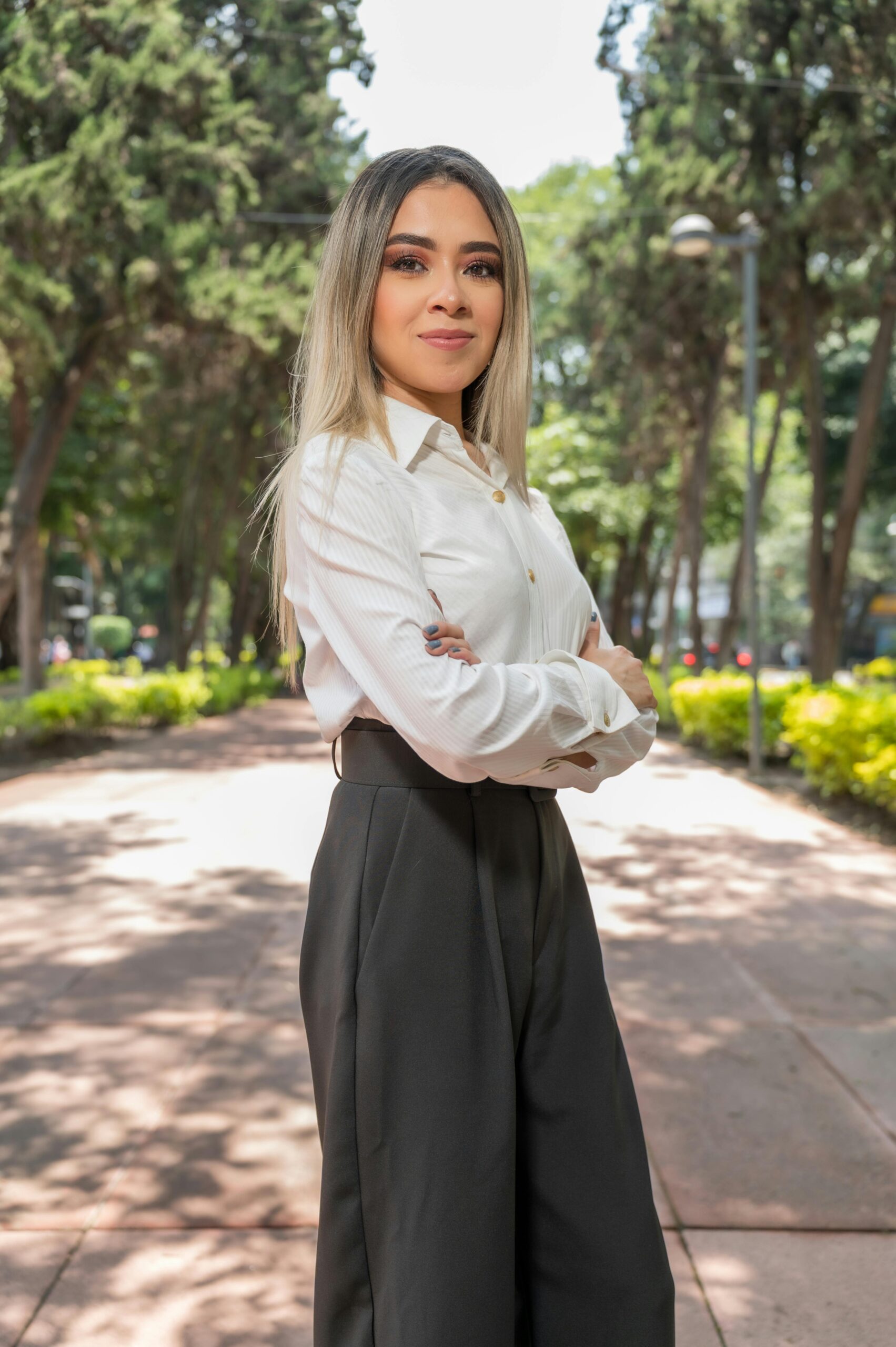 Home Portrait of a confident woman posing in a park in Ciudad de México with a sunny backdrop.
